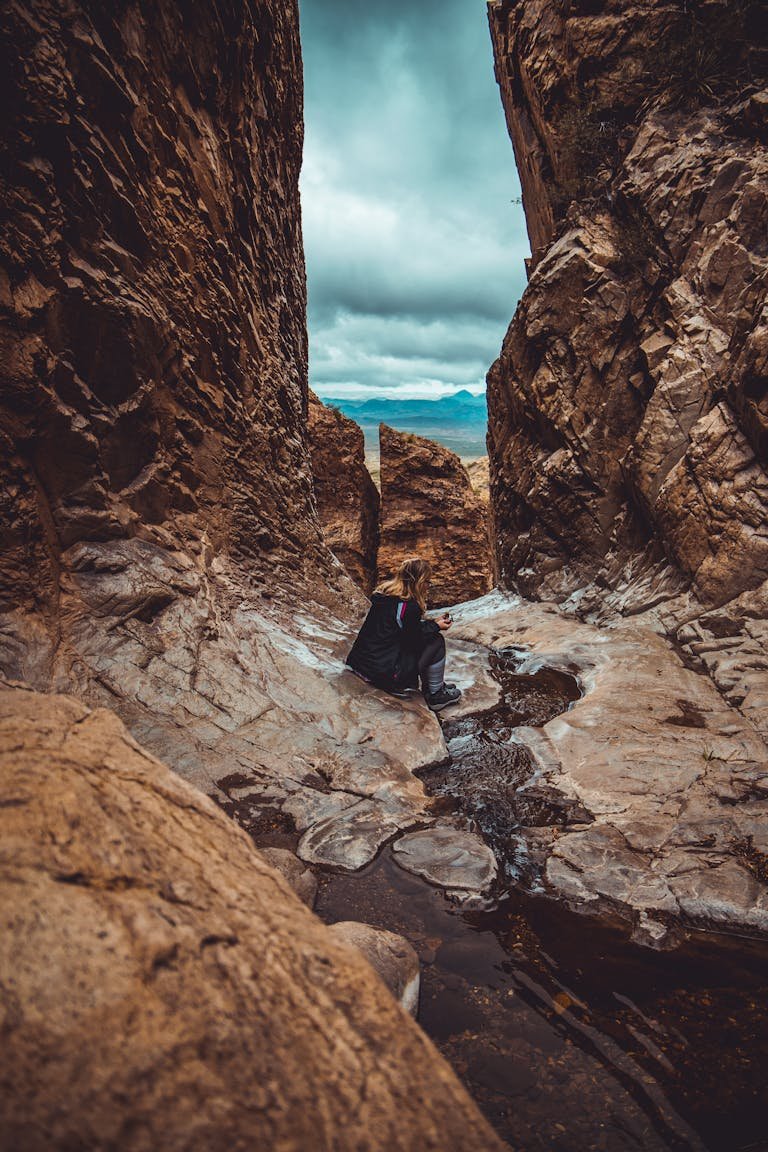 Woman sitting in a canyon stream at Big Bend National Park, Texas, exploring rock formations.