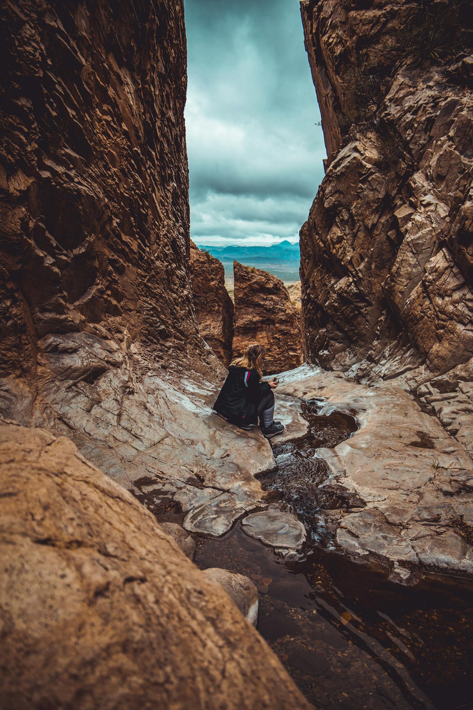 Woman sitting in a canyon stream at Big Bend National Park, Texas, exploring rock formations.